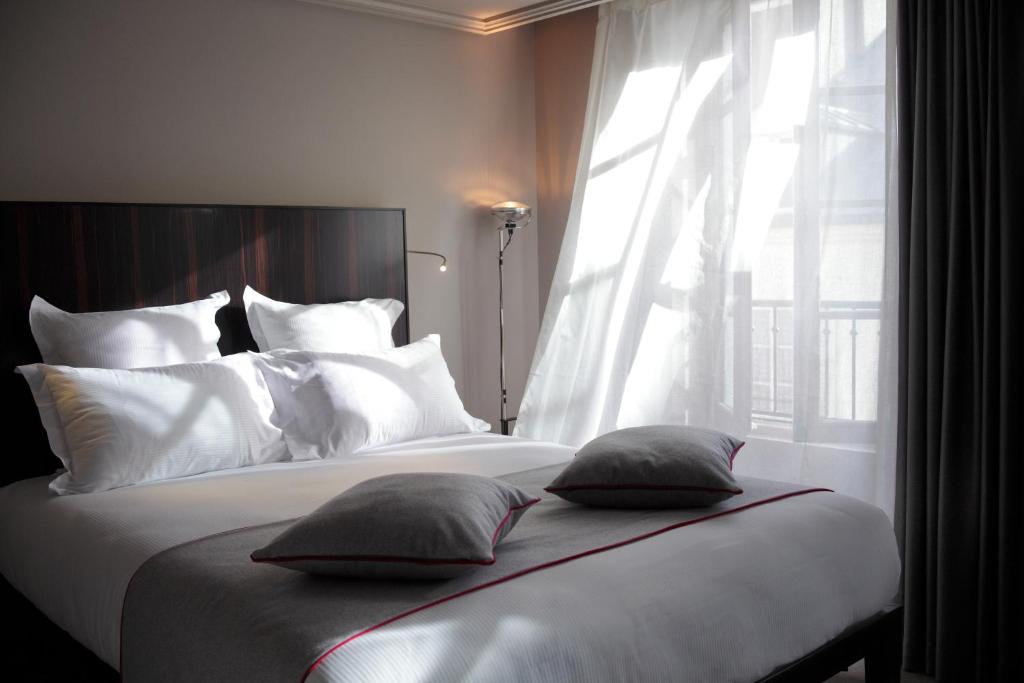 a bedroom with a bed with white pillows and a window at Hotel Saint Dominique in Paris