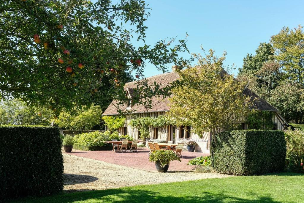 a house with a table and chairs in a garden at Maison "Jardin Gaillard" in Biéville-en-Auge