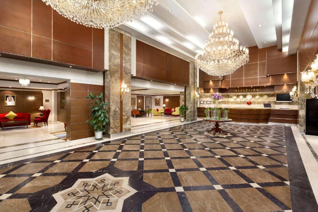 una hall con pavimento a scacchi e lampadari a braccio di Ramada by Wyndham Continental Jeddah a Gedda