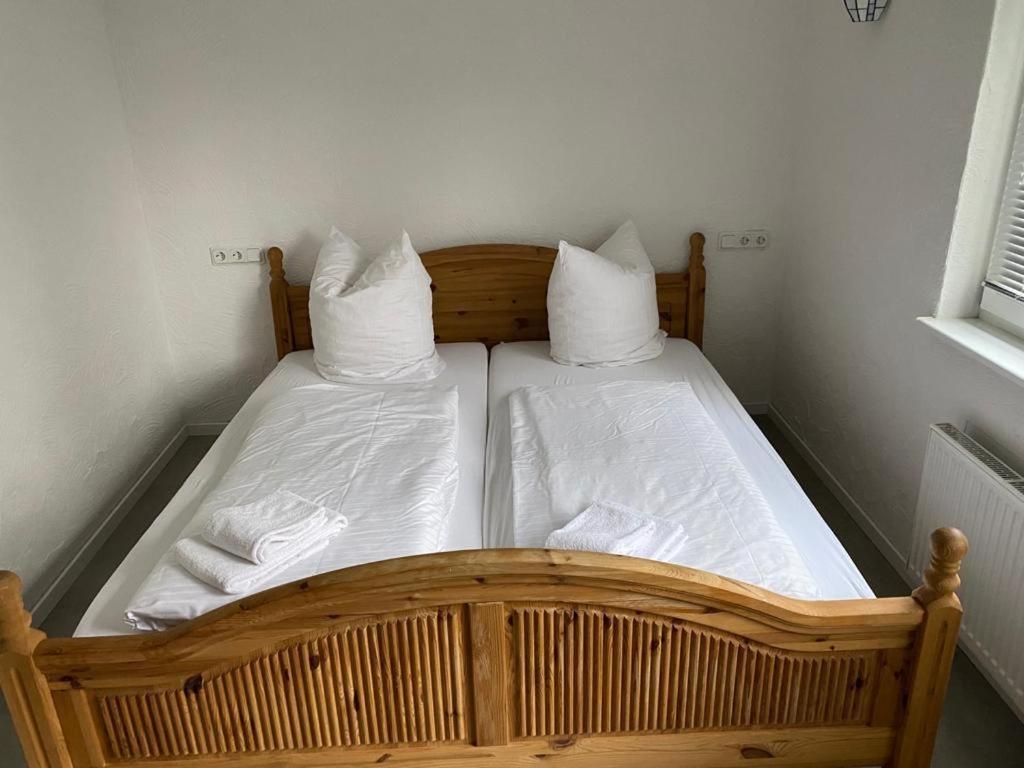 - un lit en bois avec des draps et des oreillers blancs dans l'établissement H2, à Affoldern