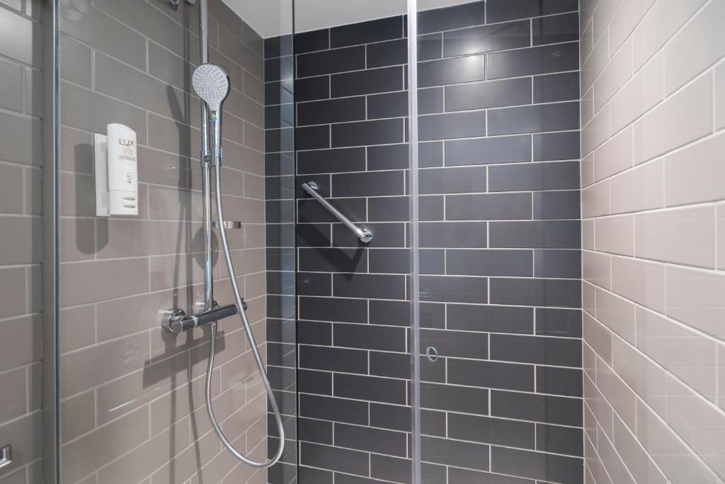 a bathroom with a shower with blue tiles at Holiday Inn Express - Paris - CDG Airport by IHG in Roissy-en-France