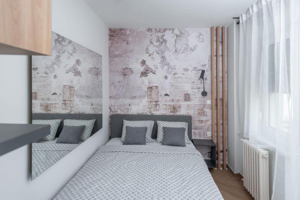 a bedroom with two beds and a brick wall at Republic Square Apartment - with garage in Novi Sad