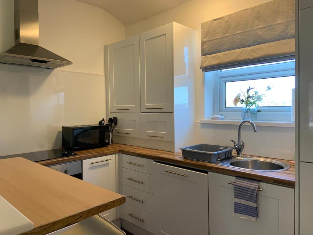 a kitchen with white cabinets and a sink and a window at Durham Serviced Properties - The Sanctuary in Durham