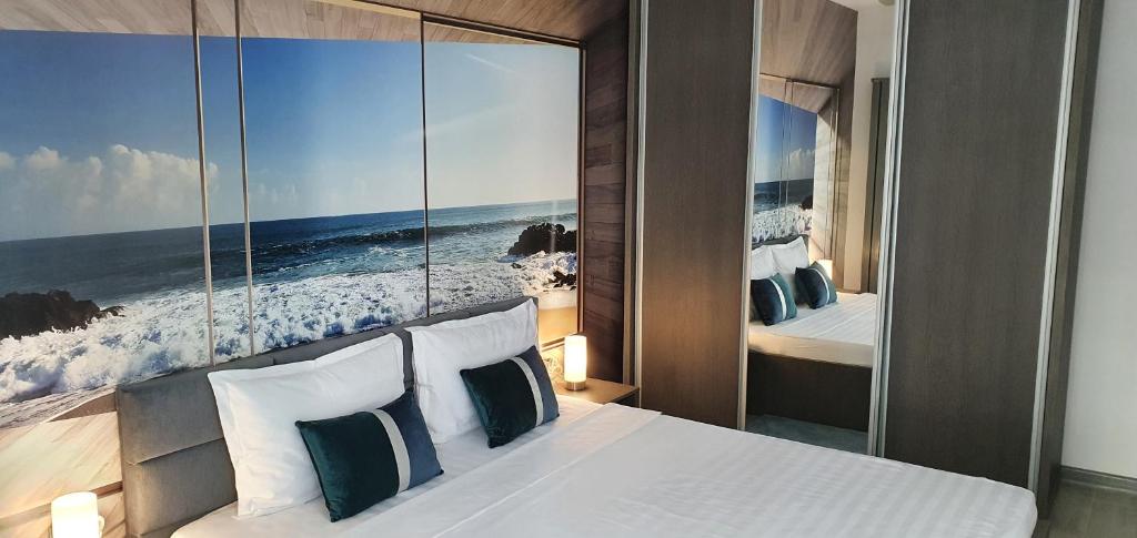 ein Schlafzimmer mit einem Bett mit einem Bild vom Meer in der Unterkunft Isabelle Apartament Alezzi Beach Resort Mamaia Nord in Mamaia Nord – Năvodari