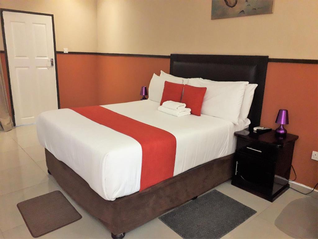 a bedroom with a large bed with red and white pillows at River View Villa Self Catering in Francistown