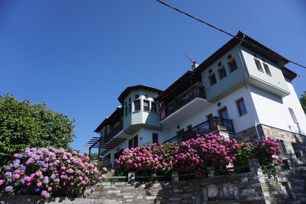 Um edifício branco com flores cor-de-rosa à frente. em Artemisia House em Tsagarada