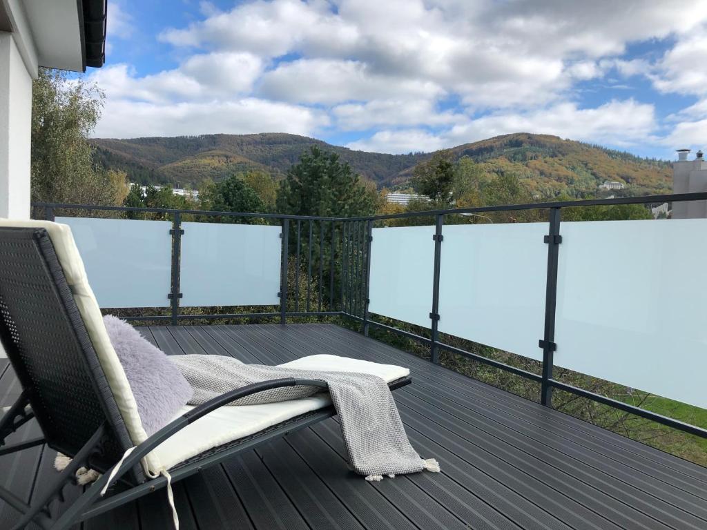 a deck with a chair and a view of mountains at Apartamenty Pod Gwiazdami in Ustroń