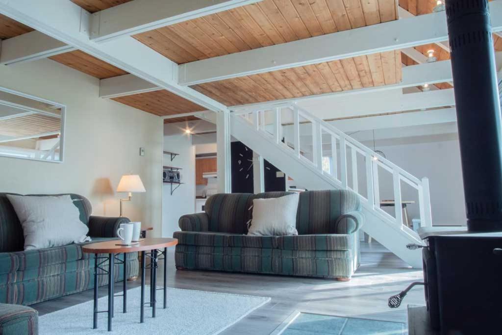 a living room with two couches and a staircase at Chalet Mont Sainte-Anne in Beaupré