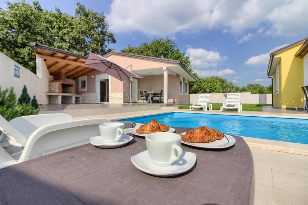 a table with food on it next to a pool at Beatiful families oriented villa Trusina with pool immersed in the nature near the town in Valtura
