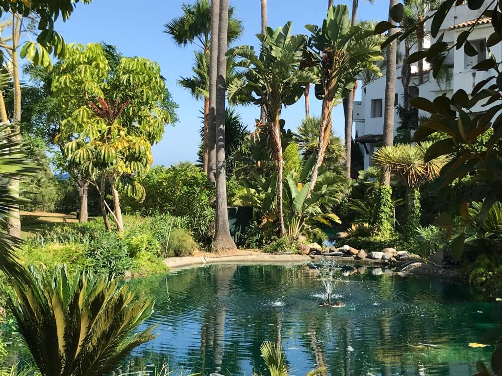 una piscina en medio de un jardín con palmeras en Apartment Costalita, direct beach access, ground floor, salt water pool, en Estepona
