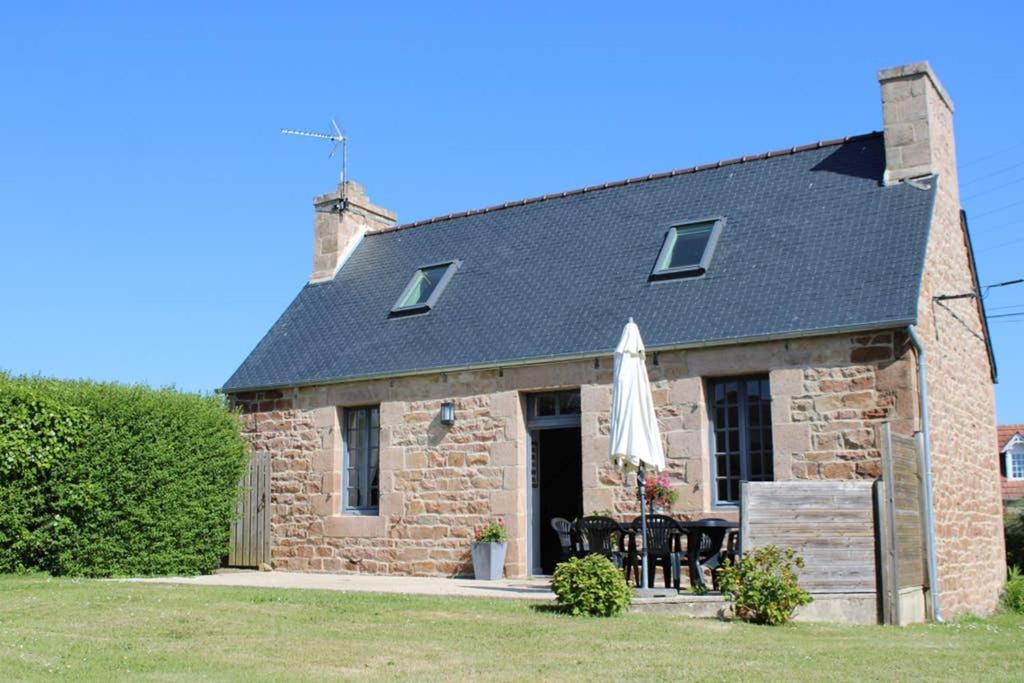 ein Steinhaus mit einem Tisch und einem Sonnenschirm in der Unterkunft La Petite Maison in Trégastel