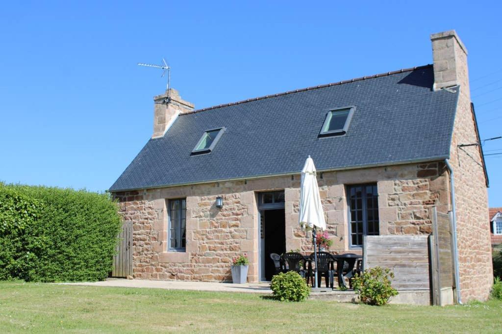 a stone house with a table and an umbrella at La Petite Maison in Trégastel