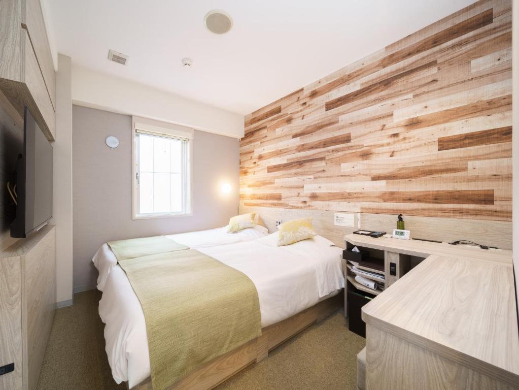 a bedroom with two beds and a wooden wall at Super Hotel Sendai Hirose Dori in Sendai