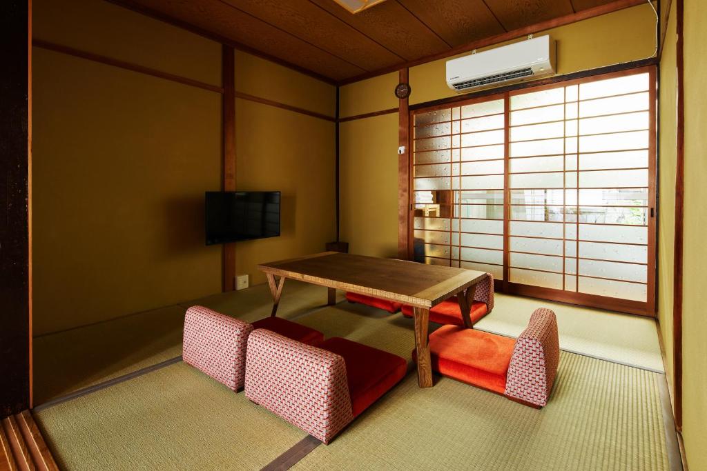 Pokój ze stołem, krzesłami i telewizorem w obiekcie Kyoto Cosy House 1946 by YADORU KYOTO HANARE w mieście Kioto