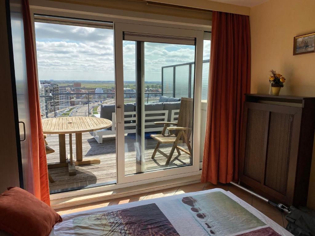 Habitación con balcón y puerta corredera grande de cristal. en ZEEPAREL Duplex loft, en Blankenberge