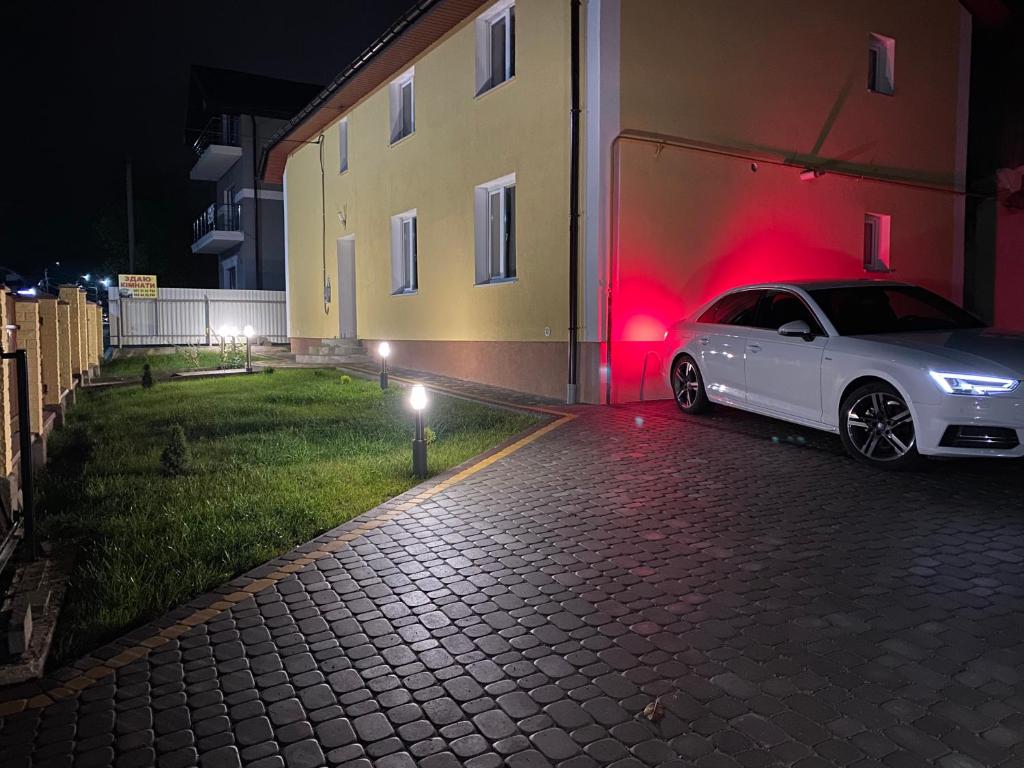 un coche blanco estacionado al lado de un edificio por la noche en Villa Vella en Skhidnitsa