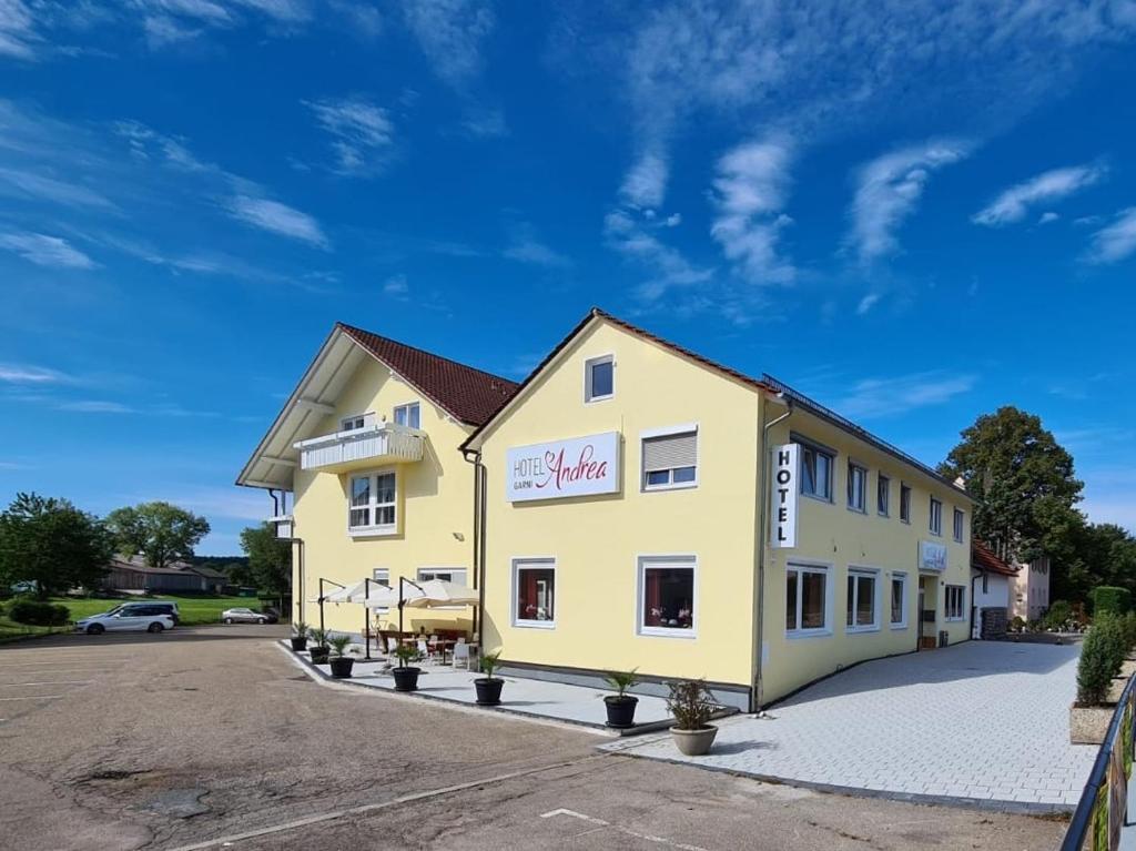 a large yellow building with a parking lot at Hotel Andrea in Crailsheim