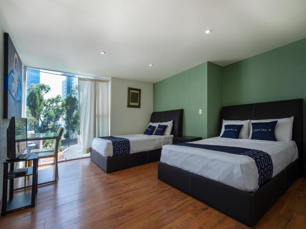 メキシコシティにあるCasa Tanimishaの緑の壁とウッドフロアの客室で、ベッド2台が備わります。