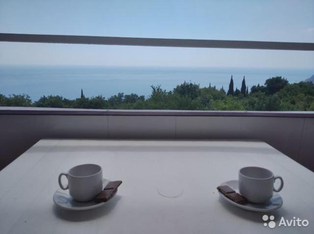 two coffee cups sitting on a table in front of a window at Кипарис in Alushta