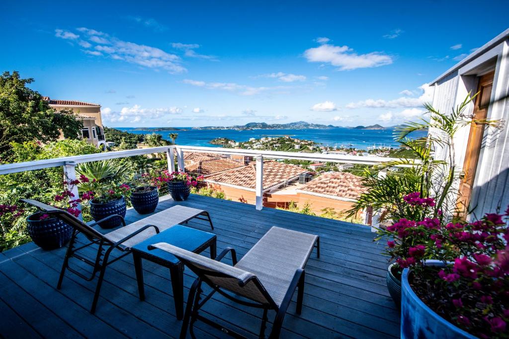 een balkon met 2 tafels en stoelen en de oceaan bij Beautiful Honeymoon Suite at Sunset Serenade in Enighed