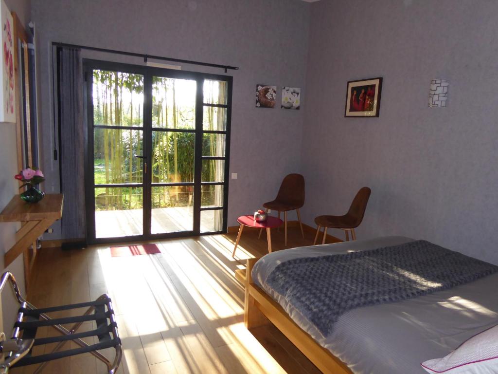 a bedroom with a bed and a sliding glass door at Le bois du drillais in La Gaubretière