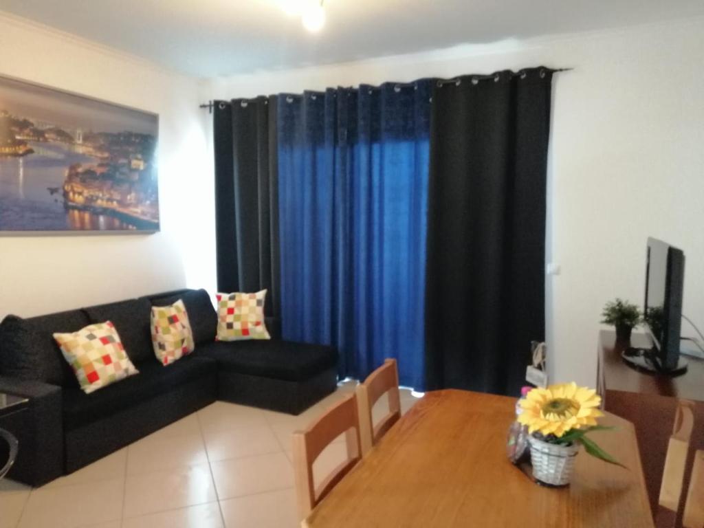 een woonkamer met een zwarte bank en een tafel bij Vilas Horizonte in Porto Santo