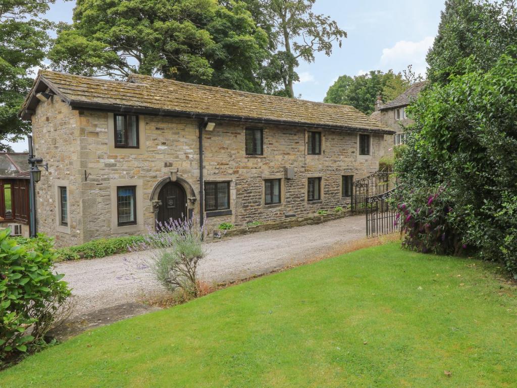 an old stone house with a yard in front of it at Ryecroft Barn in Keighley