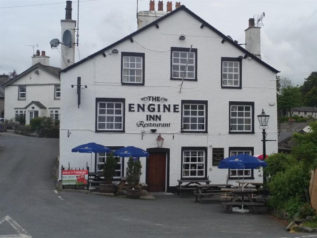 un edificio blanco con sombrillas azules delante en The Engine Inn en Holker