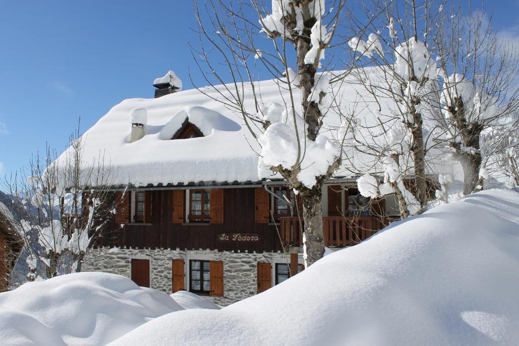 a snow covered house with a pile of snow at Chalet La Fedora - Appartements de charme in Vaujany