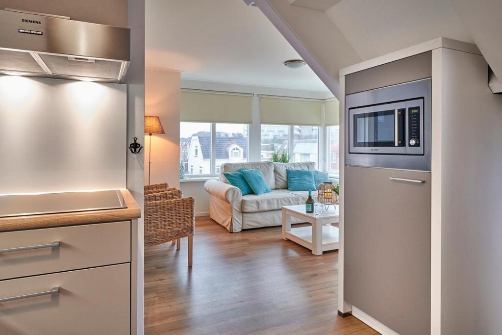 een keuken met een koelkast en een woonkamer met een bank bij Apartments Four Seasons Voorstraat in Egmond aan Zee