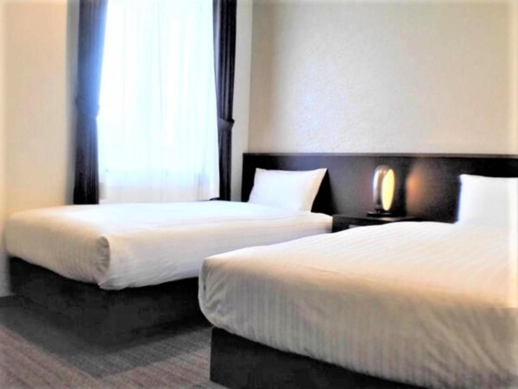 ein Hotelzimmer mit 2 Betten und einem Fenster in der Unterkunft BANDE HOTEL OSAKA - Vacation STAY 98144 in Osaka