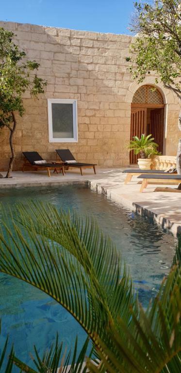 uma piscina com duas espreguiçadeiras e um edifício em Palazzo Pisani Malta B&B em Żabbar