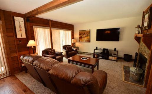 a living room with a leather couch and a table at Anaconda 101 in Copper Mountain