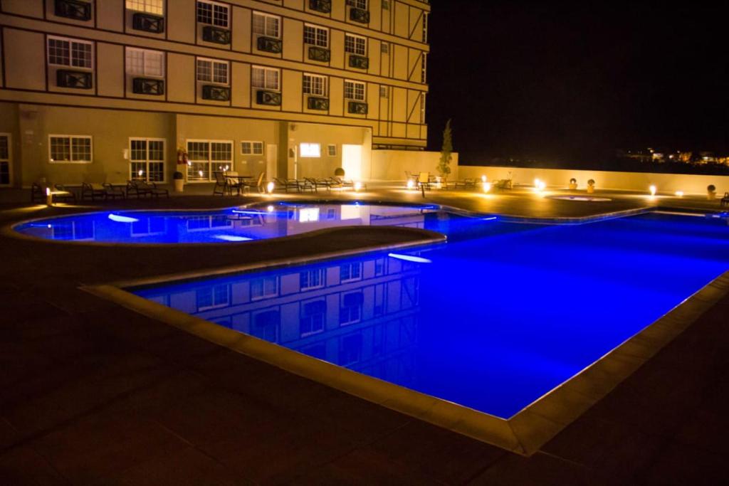 a large swimming pool with blue water at night at Resort Granja Brasil Itaipava Piscinas aquecidas in Petrópolis