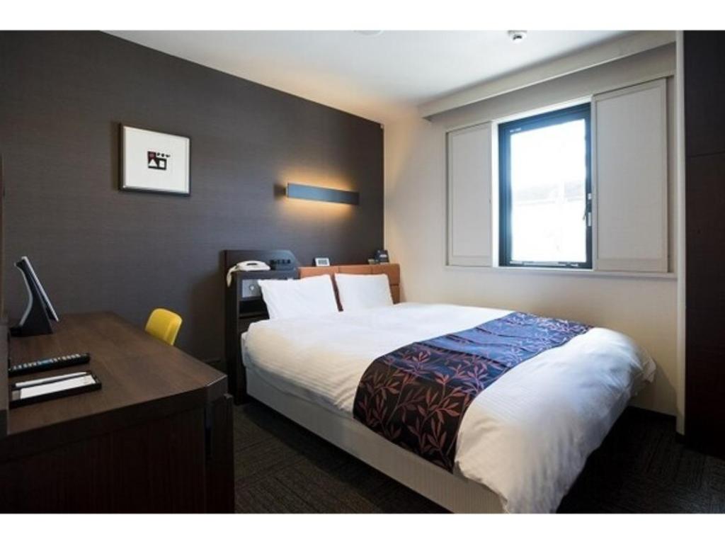 1 dormitorio con cama, escritorio y ventana en Kagoshima Plaza Hotel Tenmonkan - Vacation STAY 97891, en Kagoshima