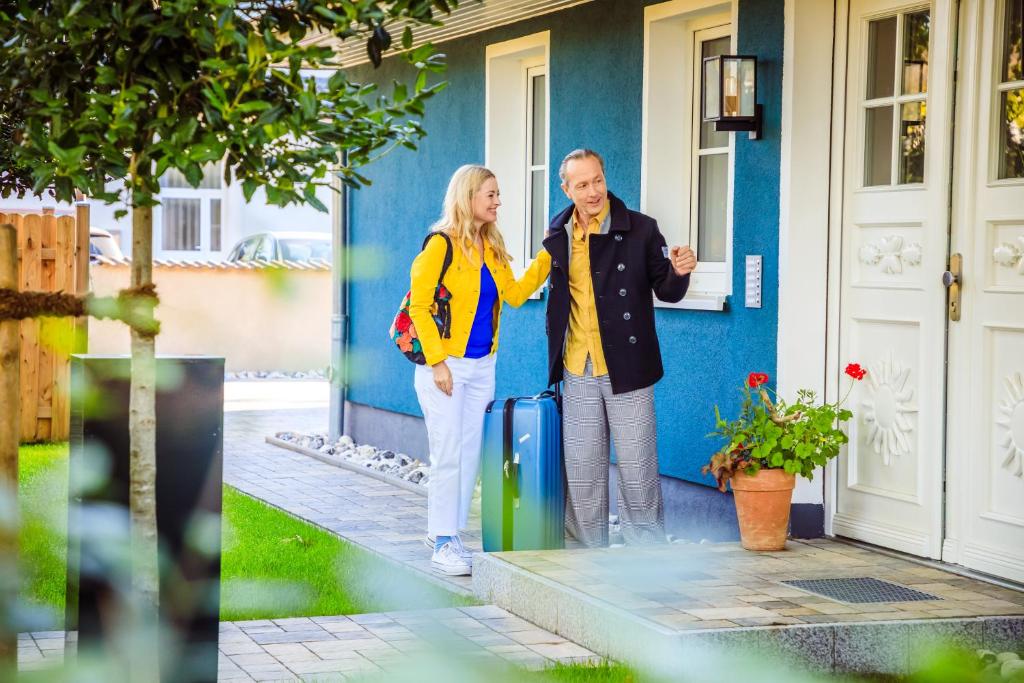 Um homem e uma mulher à porta de uma casa com uma mala. em ILEX Appartements em Born