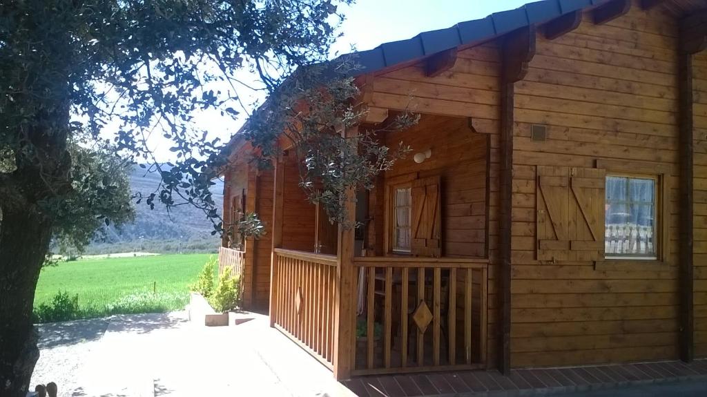 uma cabana de madeira com um alpendre e uma porta em La casa del estanque em Olocau del Rey