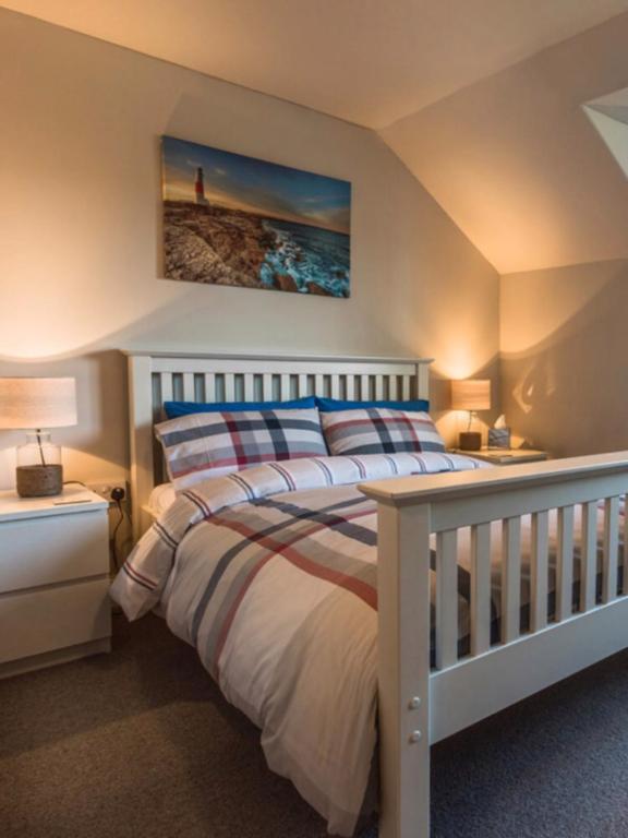 a bedroom with a white bed with two tables and two lamps at Rosslyn Cottage in Ullapool