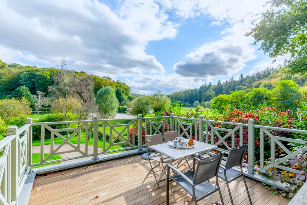 eine Holzterrasse mit einem Tisch und Stühlen darauf in der Unterkunft Le Manoir du Perroy in Saint-Wandrille-Rançon