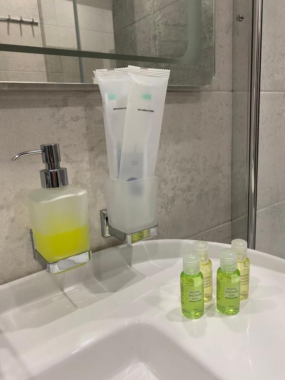 - un lavabo dans la salle de bains avec 2 bouteilles d'huiles essentielles dans l'établissement VIP Apartment Rovno & Новобудова ЖК Театральний Центр, à Rivne