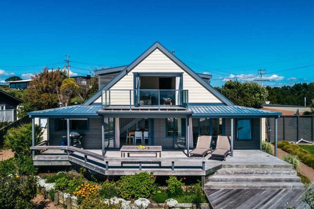 ein Haus mit einer Terrasse und zwei Stühlen darauf in der Unterkunft Noll View - Stay Waiheke in Oneroa