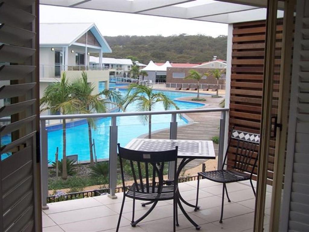 einen Balkon mit einem Tisch, Stühlen und einem Pool in der Unterkunft Oaks Pacific Blue 349 fantastic pool in Salamander Bay