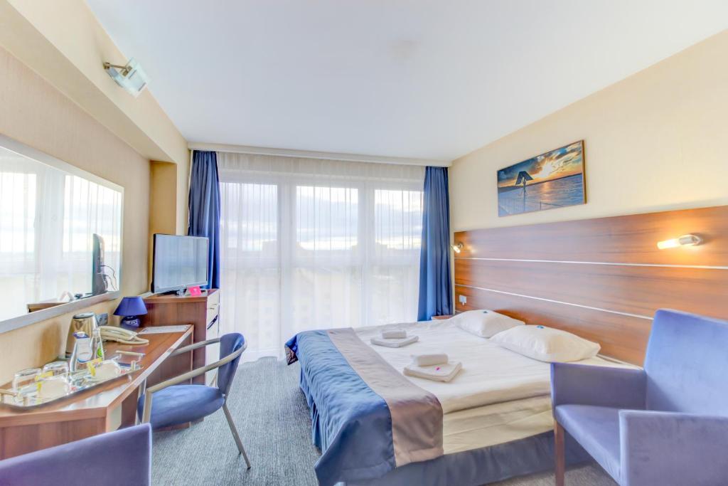 ティヒにあるHotel Tychy Primeのベッドとデスクが備わるホテルルームです。