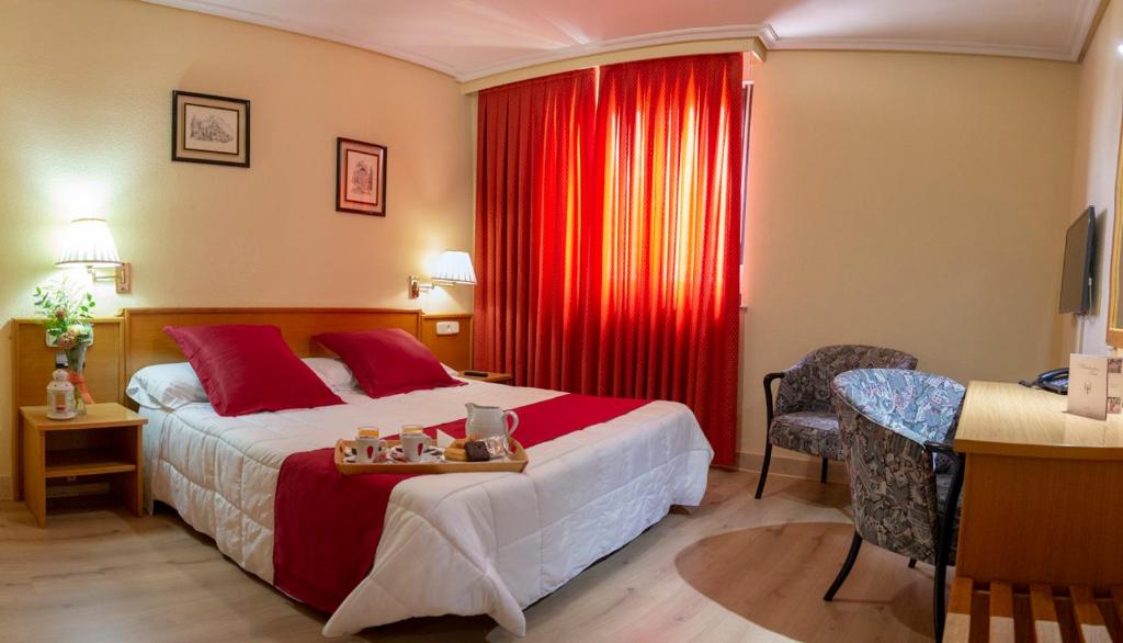 Habitación de hotel con cama y cortina roja en Hotel Helmántico, en Villares de la Reina