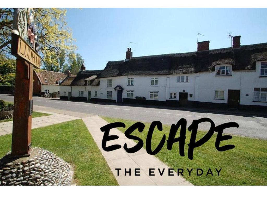 a sign that reads escape the everyday in front of a house at Bakers Cottage Ludham - Norfolk Broads in Ludham