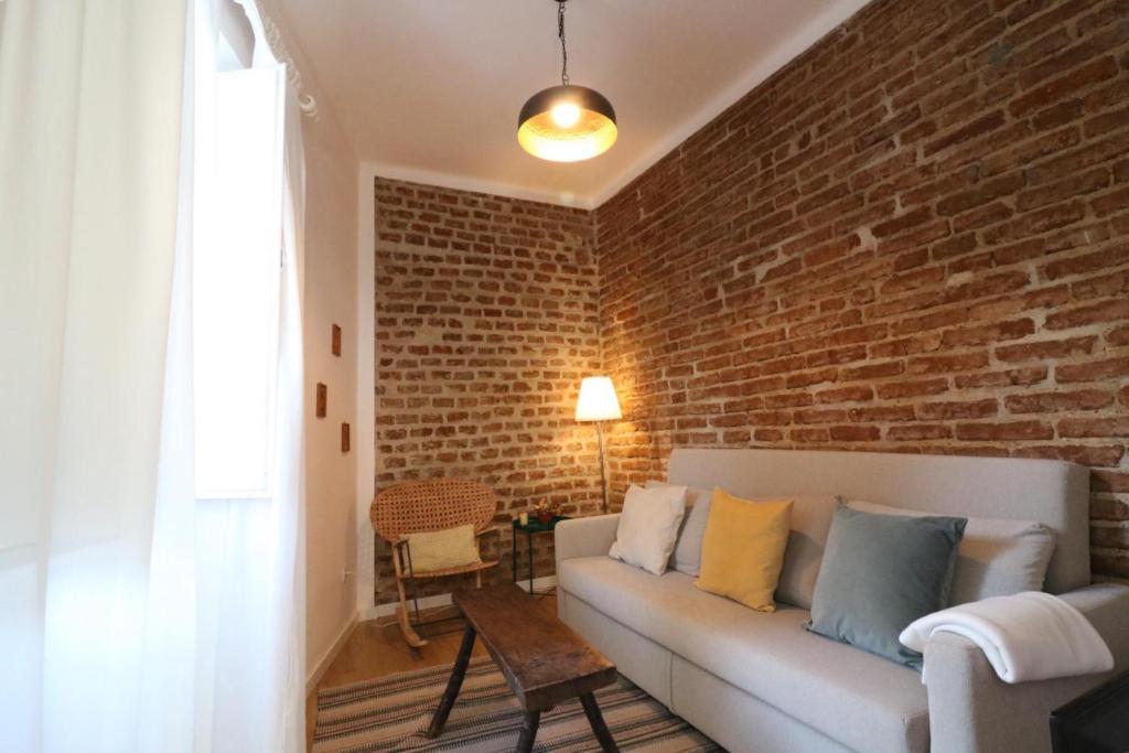 uma sala de estar com um sofá e uma parede de tijolos em Casa do Arco - Beja em Beja