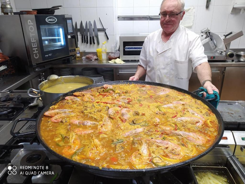 un hombre parado en una cocina con una gran pizza en Hostal Ardoi, en Zizur Mayor