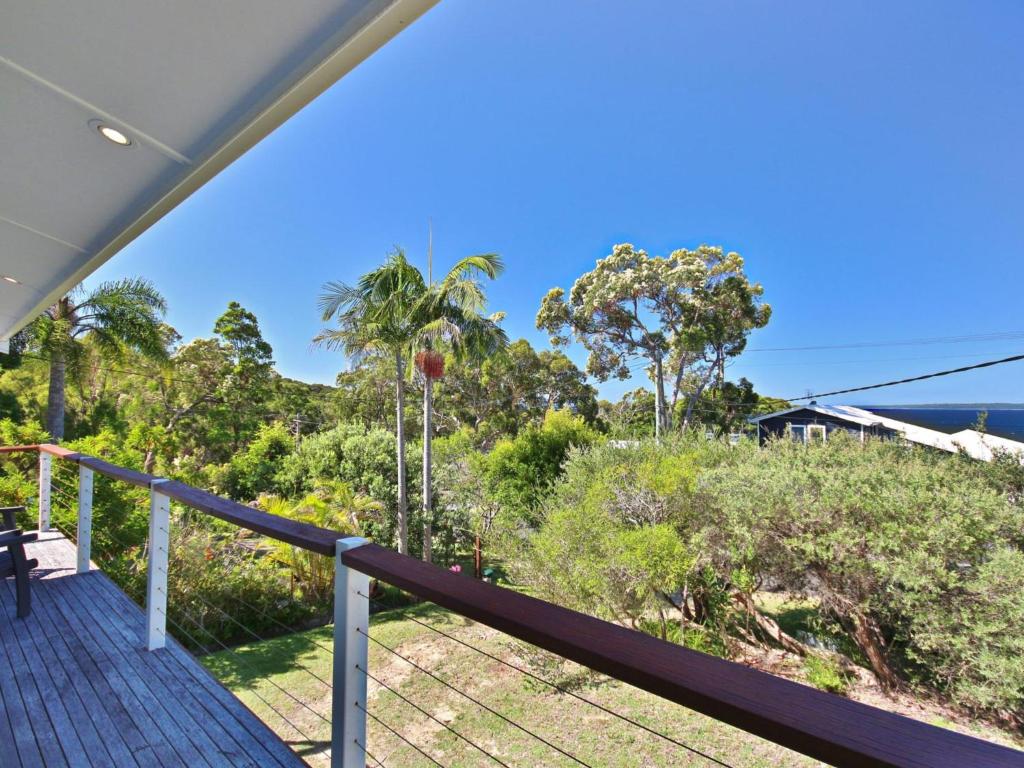 un balcon avec vue sur l'océan et les arbres dans l'établissement Acacia Cottage at Hyams Beach, à Hyams Beach