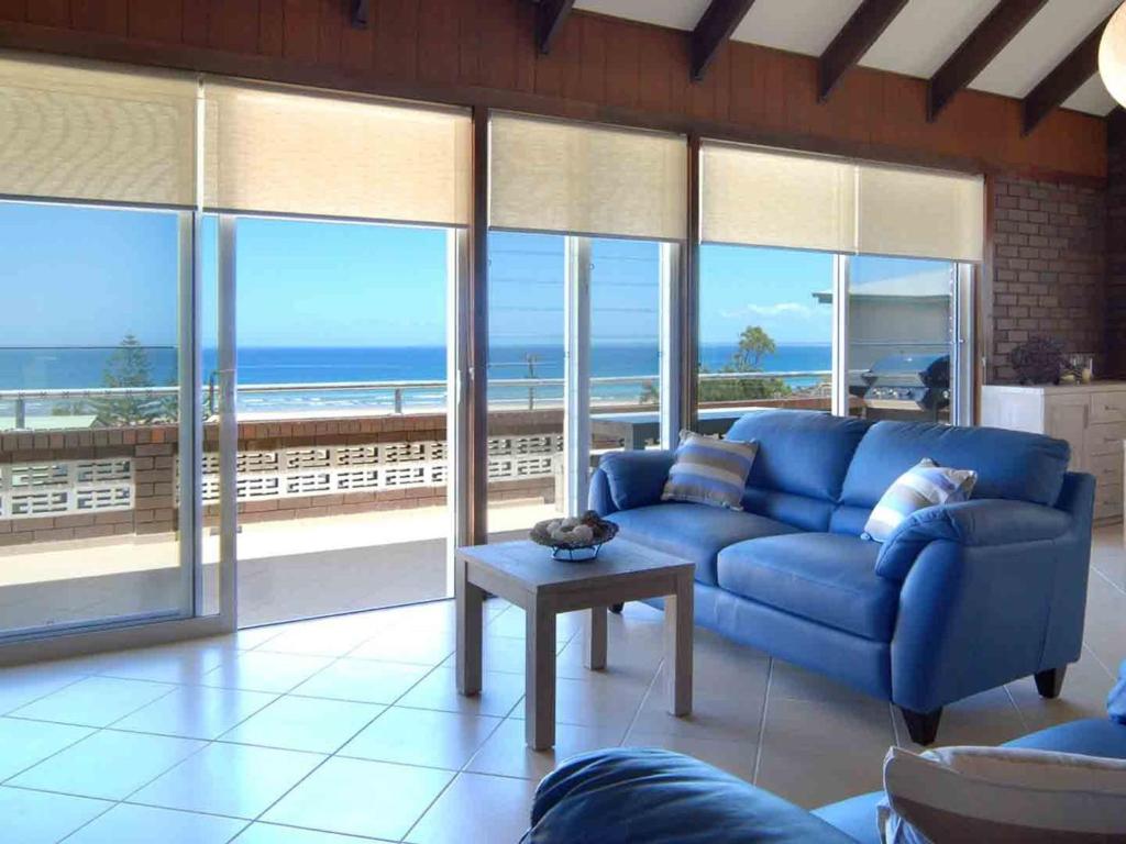 a living room with a blue couch and views of the ocean at Pinkos Gerroa in Gerroa