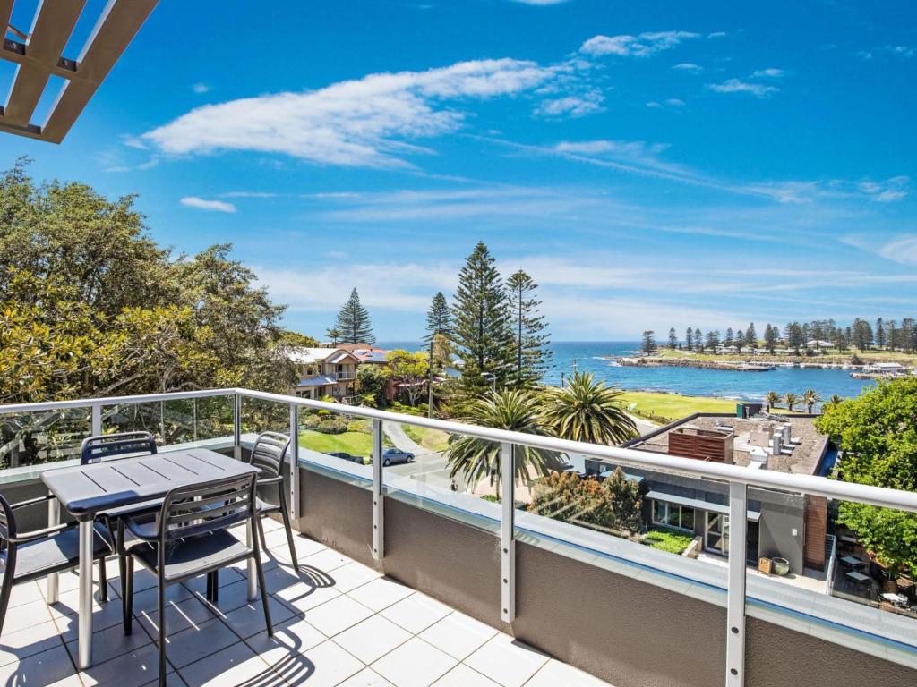 a balcony with a table and chairs and a view of the ocean at Sebel Harbourside 301 Kiama in Kiama